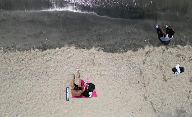 An aerial view shows beachgoers at Playa Gaira in Santa Marta, Colombia, on April 26, 2026, during the International Conference on the Just Transition Away from Fossil Fuels. (Photo by Raul ARBOLEDA / AFP)