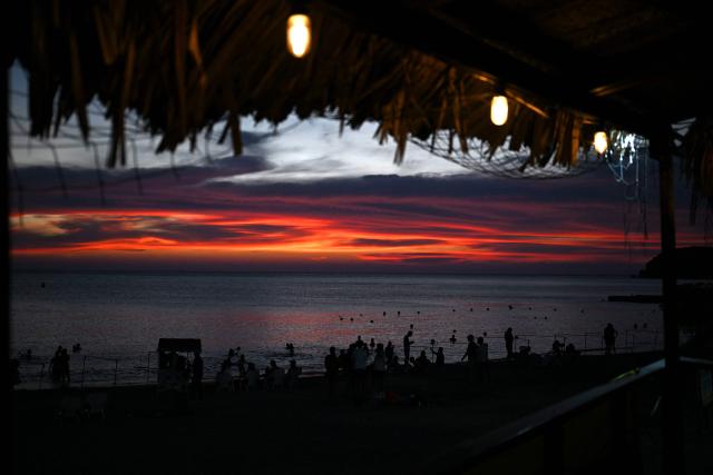 Beachgoers are seen at sunset at Pozos Colorados Beach in Santa Marta, Colombia, on April 26, 2026, during the International Conference on the Just Transition Away from Fossil Fuels. (Photo by Raul ARBOLEDA / AFP)