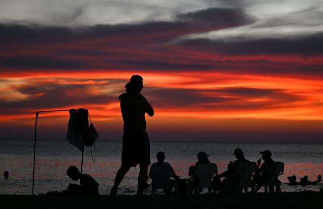 Beachgoers watch the sunset at Pozos Colorados Beach in Santa Marta, Colombia, on April 26, 2026, during the International Conference on the Just Transition Away from Fossil Fuels. (Photo by Raul ARBOLEDA / AFP)