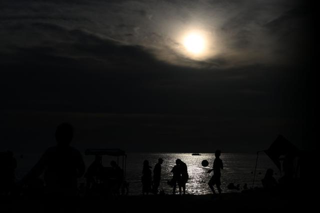 Beachgoers are seen at sunset at Pozos Colorados Beach in Santa Marta, Colombia, on April 26, 2026, during the International Conference on the Just Transition Away from Fossil Fuels. (Photo by Raul ARBOLEDA / AFP)