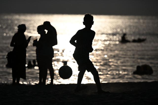 Beachgoers are seen at sunset at Pozos Colorados Beach in Santa Marta, Colombia, on April 26, 2026, during the International Conference on the Just Transition Away from Fossil Fuels. (Photo by Raul ARBOLEDA / AFP)