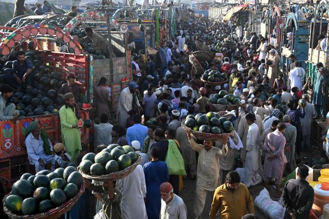 Farmers and vendors wait for customers amid truckloads of watermelons at a wholesale market in Lahore on April 27, 2026. (Photo by Arif ALI / AFP)