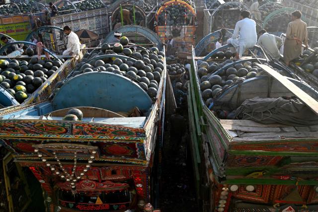 Farmers and vendors wait for customers amid truckloads of watermelons at a wholesale market in Lahore on April 27, 2026. (Photo by Arif ALI / AFP)