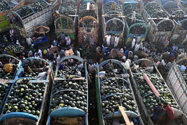 Farmers and vendors wait for customers amid truckloads of watermelons at a wholesale market in Lahore on April 27, 2026. (Photo by Arif ALI / AFP)