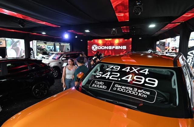 Visitors look at new cars priced in U.S. dollars during the 14th edition of Venezuela’s largest automotive exhibition, "AutoFest 2026," at the Centro Comercial Ciudad Tamanaco (CCCT) in Caracas on April 26, 2026. (Photo by Juan BARRETO / AFP)