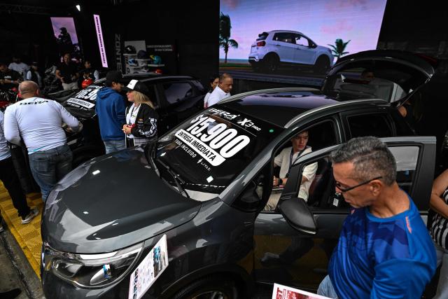 Visitors look at new cars priced in U.S. dollars during the 14th edition of Venezuela’s largest automotive exhibition, "AutoFest 2026," at the Centro Comercial Ciudad Tamanaco (CCCT) in Caracas on April 26, 2026. (Photo by Juan BARRETO / AFP)