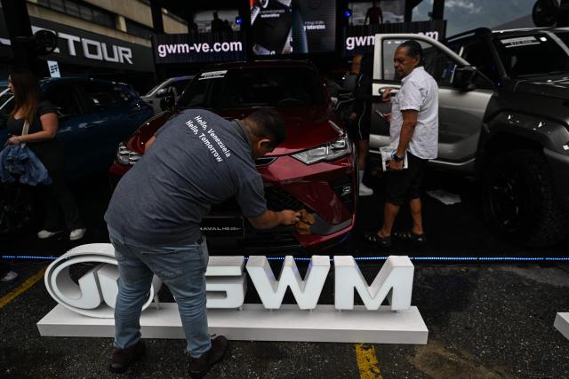 Visitors look at new cars priced in U.S. dollars during the 14th edition of Venezuela’s largest automotive exhibition, "AutoFest 2026," at the Centro Comercial Ciudad Tamanaco (CCCT) in Caracas on April 26, 2026. (Photo by Juan BARRETO / AFP)