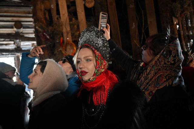 People attend celebrations of "Maslenitsa", the eastern Slavic Shrovetide in the village of Nikola-Lenivets, Kaluga region, some 220 km (140 miles) outside Moscow, on February 21, 2026, before the burning of a wooden structure called "Burning Heart" created by Russian artist Nikolay Polissky. Shrovetide or Maslenitsa is an ancient farewell ceremony to winter, traditionally celebrated in Belarus, Russia and Ukraine and involves the burning of a large effigy. (Photo by Hector RETAMAL / AFP)