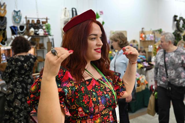 A seller tries a kokoshnik - Russian traditional headdress, at the fair of folk and arts craft of Russia, in central Moscow on March 4, 2026. (Photo by Hector RETAMAL / AFP)