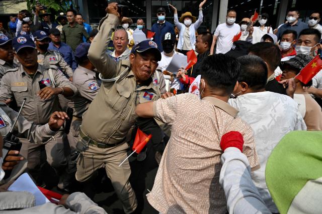 Chinese and Cambodian nationals believed to be Huione Pay creditors clash with police and security personnel during a protest near the National Bank of Cambodia (NBC) headquarters in Phnom Penh on April 27, 2026. Dozens of Chinese nationals protested outside Cambodia's central bank on April 27, calling for their accounts with a financial services firm accused of laundering illicit funds for cybercriminals to be unfrozen. (Photo by TANG CHHIN Sothy / AFP)