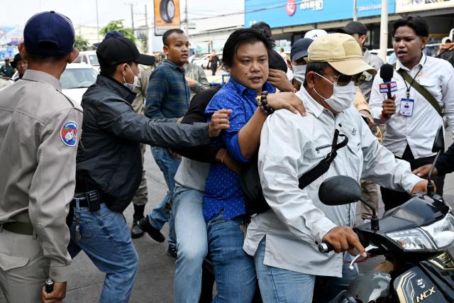 A Cambodian man (C, blue shirt) believed to be a Huione Pay creditor is arrested by police during a protest near the National Bank of Cambodia (NBC) headquarters in Phnom Penh on April 27, 2026. Dozens of Chinese nationals protested outside Cambodia's central bank on April 27, calling for their accounts with a financial services firm accused of laundering illicit funds for cybercriminals to be unfrozen. (Photo by TANG CHHIN Sothy / AFP)