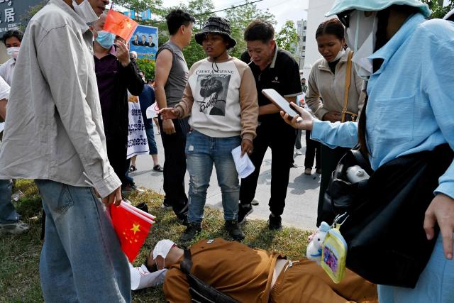 A Chinese national believed to be a Huione Pay creditor lays on the ground after being injured in clashes with police and security personnel during a protest near the National Bank of Cambodia (NBC) headquarters in Phnom Penh on April 27, 2026. Dozens of Chinese nationals protested outside Cambodia's central bank on April 27, calling for their accounts with a financial services firm accused of laundering illicit funds for cybercriminals to be unfrozen. (Photo by TANG CHHIN Sothy / AFP)