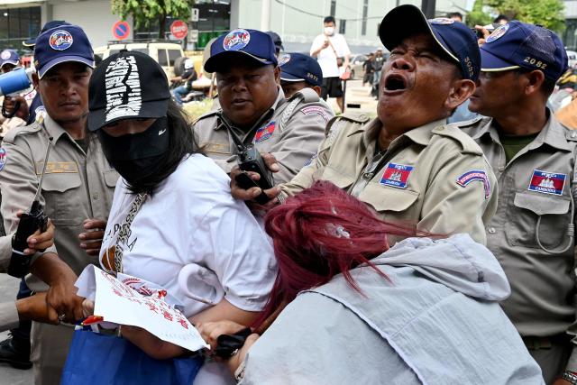 A Chinese national believed to be a Huione Pay creditor bites a security personnel during a protest near the National Bank of Cambodia (NBC) headquarters in Phnom Penh on April 27, 2026. Dozens of Chinese nationals protested outside Cambodia's central bank on April 27, calling for their accounts with a financial services firm accused of laundering illicit funds for cybercriminals to be unfrozen. (Photo by TANG CHHIN Sothy / AFP)