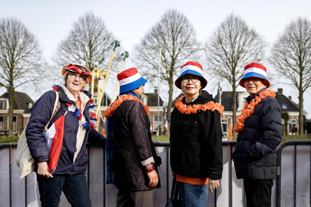 The first fans wearing orange mock flower necklaces and hats to the colours of The Netherlands' flag stand along the route the Dutch royal family is set to take as part of the King's Day celebrations through the Frisian town of Dokkum, on April 27, 2026. The Dutch King is celebrating his 59th birthday with his family in Dokkum. (Photo by Ramon van Flymen / ANP / AFP) / Netherlands OUT
