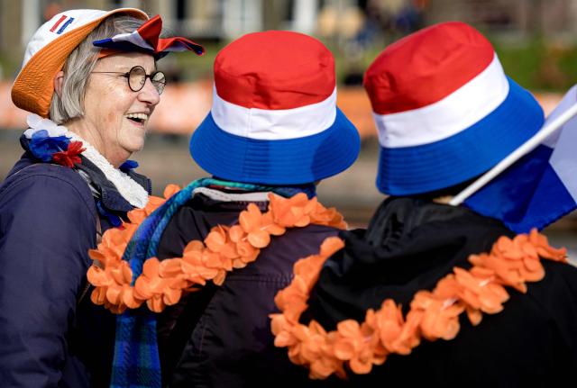 Fans wearing orange mock flower necklaces and hats to the colours of The Netherlands' flag stand along the route the Dutch royal family is set to take as part of the King's Day celebrations through the Frisian town of Dokkum, on April 27, 2026. The Dutch King is celebrating his 59th birthday with his family in Dokkum. (Photo by Ramon van Flymen / ANP / AFP) / Netherlands OUT