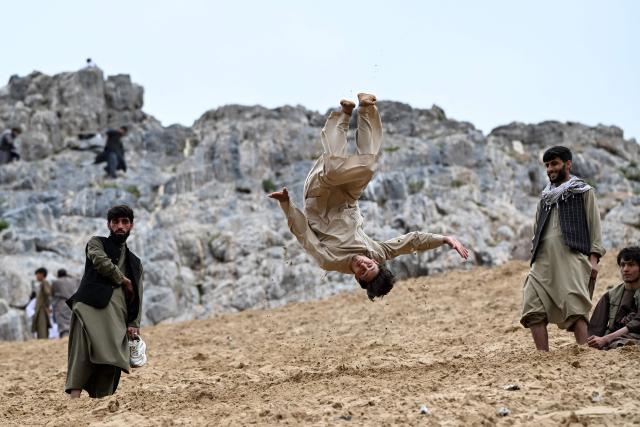 An Afghan visitor backflips down a steep and sandy mountainside on a weekend at the Sayad area of Reg-e-Rawan in Kapisa province on April 24, 2026. Hundreds of visitors travel each weekend to Reg-e-Rawan -- "the moving sands" in Dari -- to practice parkour or roll down the honey-coloured sand in Kapisa province and to unwind beside breathtaking views. (Photo by Wakil KOHSAR / AFP)