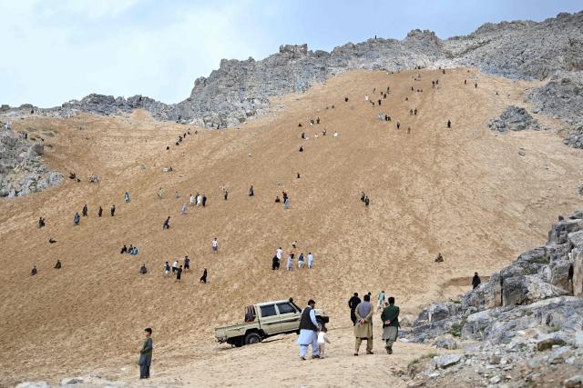 Afghan visitors enjoy rolling down a steep and sandy mountainside on a weekend at the Sayad area of Reg-e-Rawan in Kapisa province on April 24, 2026. Hundreds of visitors travel each weekend to Reg-e-Rawan -- "the moving sands" in Dari -- to practice parkour or roll down the honey-coloured sand in Kapisa province and to unwind beside breathtaking views. (Photo by Wakil KOHSAR / AFP)