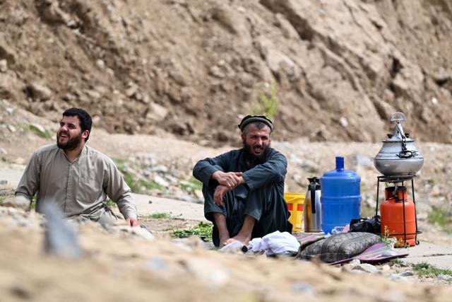 Afghan men picnic and enjoy the view of a steep and sandy mountainside on a weekend at the Sayad area of Reg-e-Rawan in Kapisa province on April 24, 2026. Hundreds of visitors travel each weekend to Reg-e-Rawan -- "the moving sands" in Dari -- to practice parkour or roll down the honey-coloured sand in Kapisa province and to unwind beside breathtaking views. (Photo by Wakil KOHSAR / AFP)