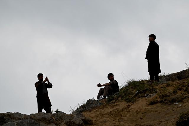 An Afghan visitors take photos on a mountainside at the Sayad area of Reg-e-Rawan in Kapisa province on April 24, 2026. Hundreds of visitors travel each weekend to Reg-e-Rawan -- "the moving sands" in Dari -- to practice parkour or roll down the honey-coloured sand in Kapisa province and to unwind beside breathtaking views. (Photo by Wakil KOHSAR / AFP)