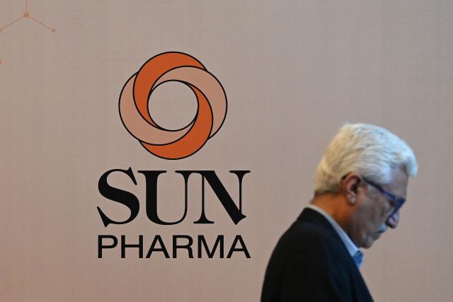 A man walks past the logo of Sun Pharmaceutical is pictured ahead of a press conference in Mumbai on April 27, 2026. India's Sun Pharmaceutical on April 27 said it had agreed to buy women's healthcare firm Organon in a deal that values the US drugmaker at $11.75 billion. (Photo by Punit PARANJPE / AFP)