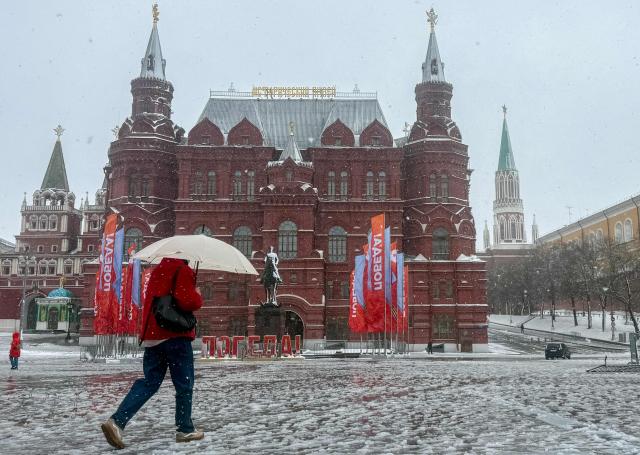 A person shelters from snow under an umbrella while walking outside the Kremlin during a snowstorm in Moscow on April 27, 2026. (Photo by Andrey BORODULIN / AFP)