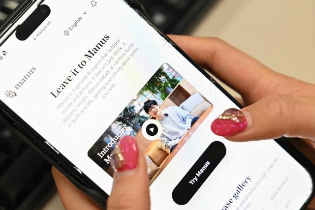 (FILES) A photo illustration taken in Beijing on March 11, 2025 shows a mobile phone displaying an introduction screen for the AI assistant tool Manus, released by Chinese startup Butterfly Effect. China has blocked Meta's acquisition of AI startup Manus, the country's top economic planning body said on April 27, 2026, following media reports last month that Beijing had restricted two co-founders from leaving the country. (Photo by ADEK BERRY / AFP)