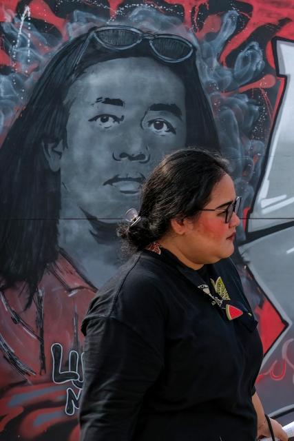 A visitor walks past a mural featuring Andrie Yunus, the deputy coordinator of the KontraS rights group who suffered serious injuries when two men on a scooter threw acid at him, at the Mural Exhibition "From Citizens for Andrie" in Jakarta on April 27, 2026. The head of Indonesia's military intelligence has stepped down after four members of his unit were arrested over an acid attack on an activist critical of the military's growing role in government, according to a spokesman from the armed forces. (Photo by BAY ISMOYO / AFP)