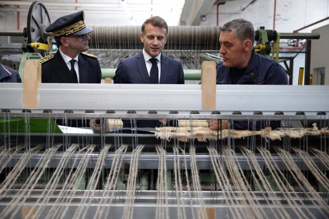 France's President Emmanuel Macron (C) listens to explanations as he visits the future site of the Occitanie Géotex plant, which will manufacture geotextiles for construction, roads, and agriculture using plant-based hemp fibers and wool produced in the region, in Laroque-d'Olmes, south-western France, on April 27, 2026. Emmanuel Macron will travel to south western France's Ariège department on April 27, 2026, a trip focused on reindustrialization and health, before a two-day visit to the microstate of Andorra of which his is also Co-Prince, where the sensitive issue of abortion will be discussed. (Photo by Valentine CHAPUIS / POOL / AFP)