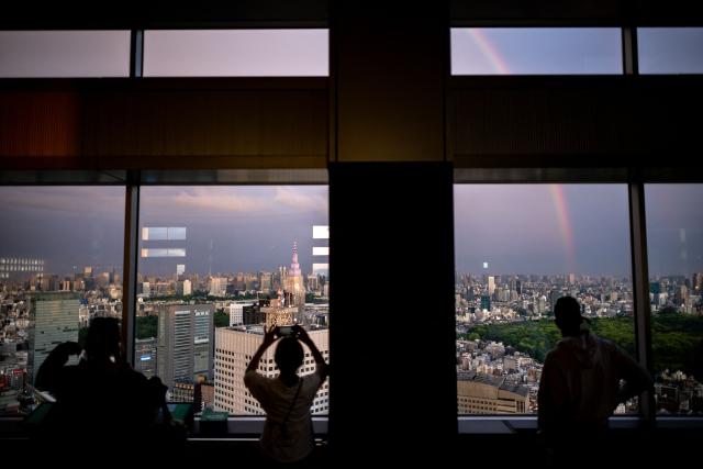 Visitors look out from the windows of the observation deck at the Tokyo Metropolitan Government building in the Shinjuku area of central Tokyo on April 27, 2026. (Photo by Philip FONG / AFP)