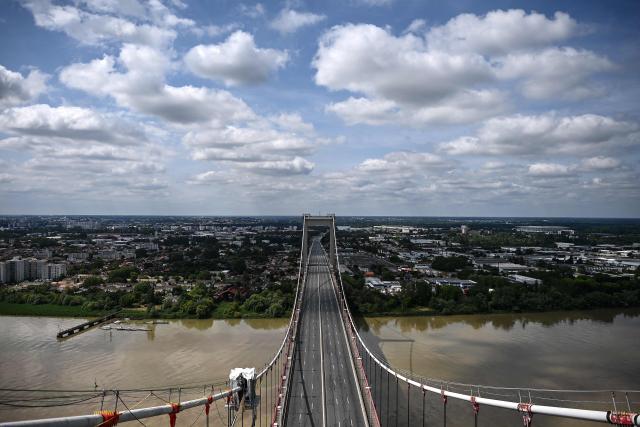 Workers stand on the deck of the closed Pont d'Aquitaine (Aquitaine bridge) at the end of a maintenance operation in Bordeaux, south-western France, on April 26, 2026. Routine maintenance work is carried out regularly on the suspension Aquitaine bridge connecting Bordeaux and its northern suburb of Lormont over the Garonne river. Triggering the closure of Bordeaux's ring road, maintenance work on the second-longest suspension bridge in France is generally performed at night or during week-ends. (Photo by Christophe ARCHAMBAULT / AFP)