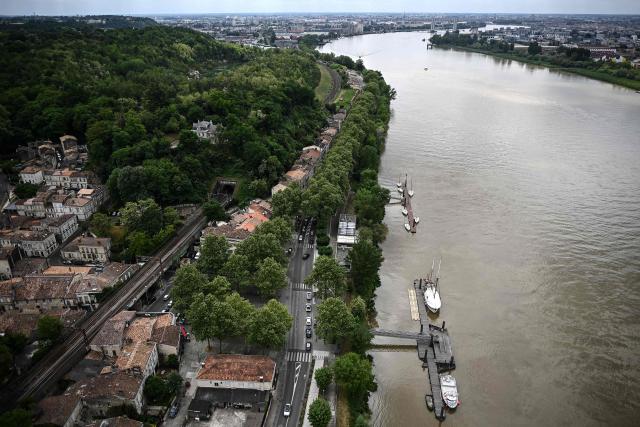 This picture shows the Bordeaux suburb of Lormont (L) with moored boats along the Garonne river as seen from the top of the Pont d'Aquitaine (Aquitaine bridge) during a maintenance operation in Bordeaux, south-western France, on April 26, 2026. Routine maintenance work is carried out regularly on the suspension Aquitaine bridge connecting Bordeaux and its northern suburb of Lormont over the Garonne river. Triggering the closure of Bordeaux's ring road, maintenance work on the second-longest suspension bridge in France is generally performed at night or during week-ends. (Photo by Christophe ARCHAMBAULT / AFP)