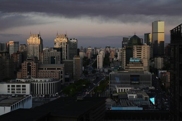 Light reflects off buildings at dusk in Beijing on April 27, 2026. (Photo by GREG BAKER / AFP)
