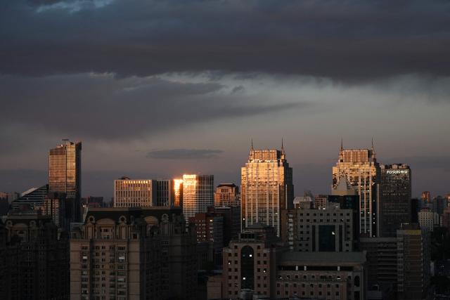 Light reflects off buildings at sunset in Beijing on April 27, 2026. (Photo by GREG BAKER / AFP)