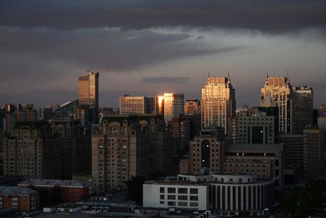 Light reflects off buildings at sunset in Beijing on April 27, 2026. (Photo by GREG BAKER / AFP)