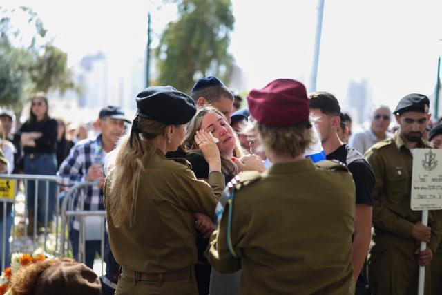 Israeli soldiers comfort a family member grieving during the funeral of Sergeant Idan Fooks in Petah Tikva on April 27, 2026. The Israeli military said on April 26 that a soldier was killed in southern Lebanon, where a ceasefire has been in place since mid-April. Sergeant Idan Fooks, 19, died "during combat" in south Lebanon, while "an officer and three additional soldiers were severely injured, along with a soldier who was moderately injured and a soldier who was lightly injured", the military said. (Photo by Ilia YEFIMOVICH / AFP) / 