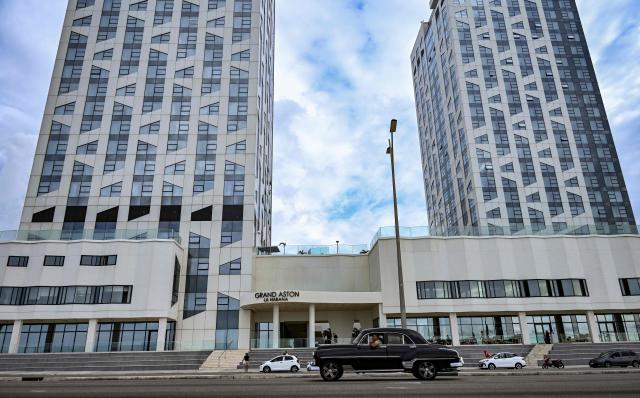 (FILES) A classic American car drives past the Grand Aston La Habana hotel in Havana on March 12, 2026. Tourist arrivals in Cuba plummeted in the first quarter of 2026, affected by the US fuel embargo and the suspension of international flights. Between January and March, the island received 298,057 foreign visitors, 48% fewer than in the same period in 2025, according to figures published by the National Office for Statistics and Information. (Photo by YAMIL LAGE / AFP)