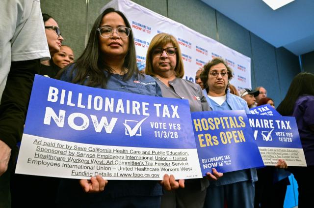 Healthcare workers and other supporters with the Billionaire Tax Now coalition hold placards during a media briefing in Los Angeles on April 27, 2026. Healthcare workers and allies outlined the next steps in their effort to get California's Billionaire Tax on the ballot for the November election, with their efforts already exceeding 1,500,000 signatures collected from across the state. The initiative would levy a one-time 5% tax on California billionaires. (Photo by Frederic J. BROWN / AFP)