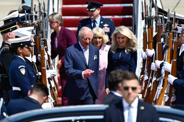 Britain's King Charles III and Britain's Queen Camilla walk past an honor guard with US Protocol Chief Monica Crowley (R) after arriving at Joint Base Andrews, Maryland, on April 27, 2026. King Charles III arrives in Washington Monday for a high-stakes state visit aimed at salvaging Britain's frayed ties with Donald Trump, amid extra-tight security following an attack on a gala dinner attended by the US president. Tensions over the Iran war have rocked the so-called "special relationship" ahead of a trip that was meant to mark the United States' 250th anniversary of independence from the British monarch's ancestors. (Photo by Kent NISHIMURA / AFP)