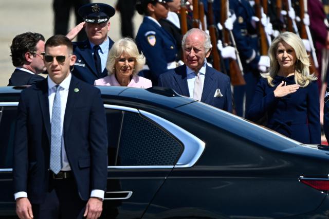 Britain's King Charles III and Britain's Queen Camilla walk toward an awaiting vehicle flanked by US Protocol Chief Monica Crowley (R) after arriving at Joint Base Andrews, Maryland, on April 27, 2026. King Charles III arrives in Washington Monday for a high-stakes state visit aimed at salvaging Britain's frayed ties with Donald Trump, amid extra-tight security following an attack on a gala dinner attended by the US president. Tensions over the Iran war have rocked the so-called "special relationship" ahead of a trip that was meant to mark the United States' 250th anniversary of independence from the British monarch's ancestors. (Photo by Kent NISHIMURA / AFP)