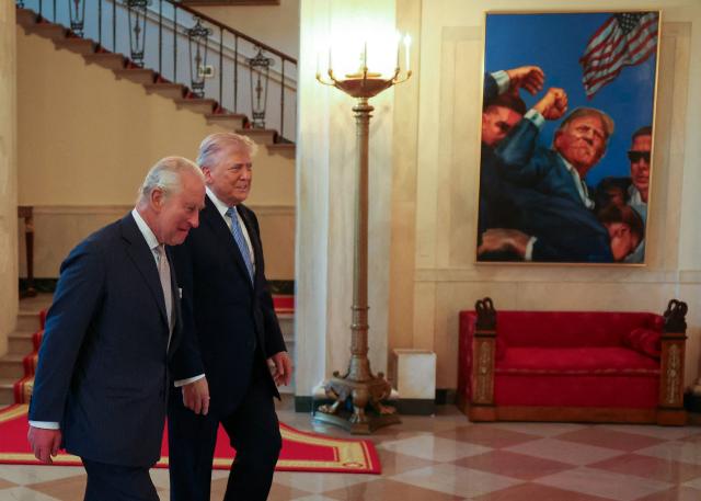 Britain's King Charles III and US President Donald Trump walk past a painting depicting Trump's assassination attempt in 2024 while touring the White House in Washington, DC, on April 27, 2026. (Photo by Suzanne Plunkett / POOL / AFP)
