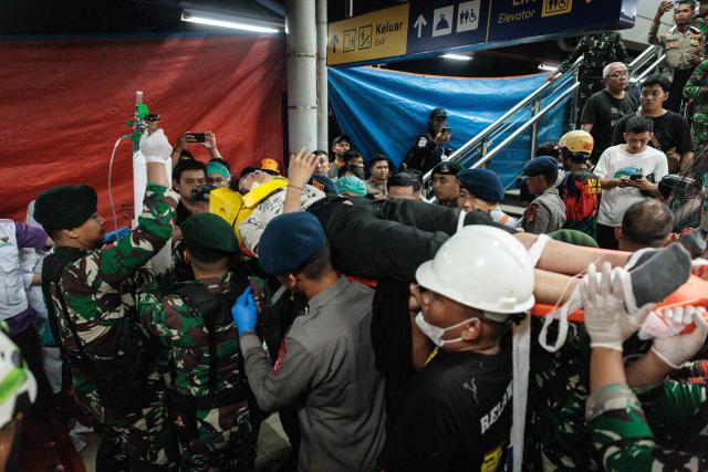 Rescuers carry out a survivor trapped inside a carriage after a passenger train locomotive pierced through the rear car of a commuter train at Bekasi Timur station in Bekasi, West Java on April 28, 2026. (Photo by Yasuyoshi Chiba / AFP)
