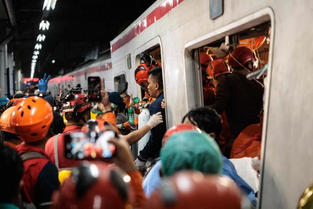 Rescuers work to save five survivors trapped inside a carriage after a passenger train locomotive pierced through the rear car of a commuter train at Bekasi Timur station in Bekasi, West Java on April 28, 2026. (Photo by Yasuyoshi Chiba / AFP)