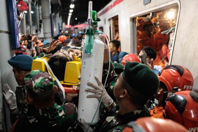 Rescuers carry out a survivor trapped inside a carriage after a passenger train locomotive pierced through the rear car of a commuter train at Bekasi Timur station in Bekasi, West Java on April 28, 2026. (Photo by Yasuyoshi Chiba / AFP)