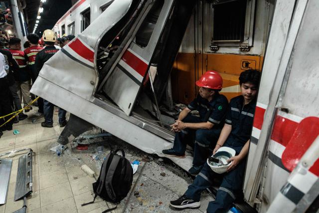 Workers sit at the site of a train collision as rescuers work to save five survivors trapped inside a carriage after a passenger train locomotive pierced through the rear car of a commuter train at Bekasi Timur station in Bekasi, West Java on April 28, 2026 (Photo by Yasuyoshi Chiba / AFP)
