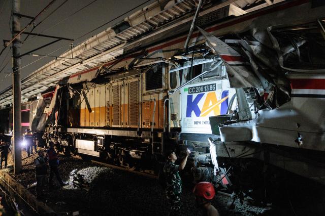 Security officers check the site of a train collision as rescuers work to save five survivors trapped inside a carriage after a passenger train locomotive pierced through the rear car of a commuter train at Bekasi Timur station in Bekasi, West Java on April 28, 2026. (Photo by Yasuyoshi Chiba / AFP)