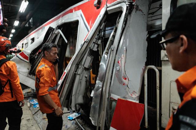 Rescue members check the site of a train collision as rescuers work to save five survivors trapped inside a carriage after a passenger train locomotive pierced through the rear car of a commuter train at Bekasi Timur station in Bekasi, West Java on April 28, 2026. (Photo by Yasuyoshi Chiba / AFP)