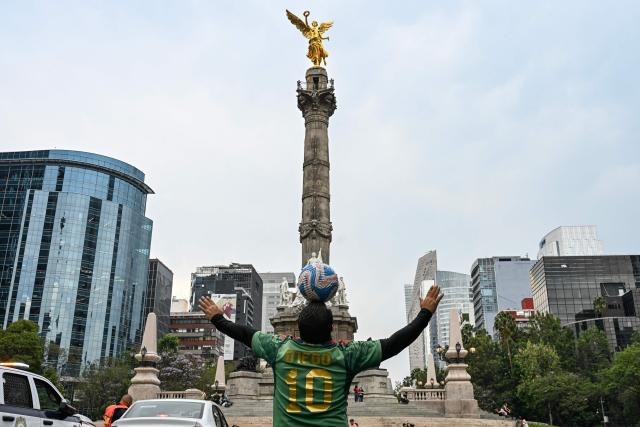 Former Mexican footballer Diego Ivan Carmona, 40, performs a freestyle routine with a ball on a traffic light in front of the Angel of Independence monument in Mexico City on April 27, 2026. Mexico will co-host the biggest World Cup in history along with the United States and Canada from June 11 to July 19, 2026. (Photo by Yuri CORTEZ / AFP)