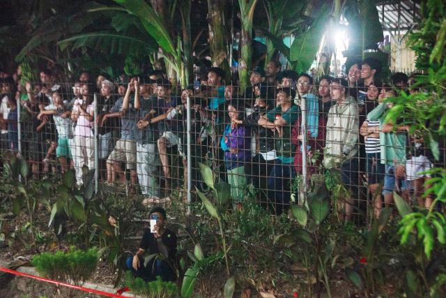 People watch after a passenger train locomotive pierced through the rear car of a commuter train at Bekasi Timur station in Bekasi, West Java on April 28, 2026. (Photo by Aditya Irawan / AFP)
