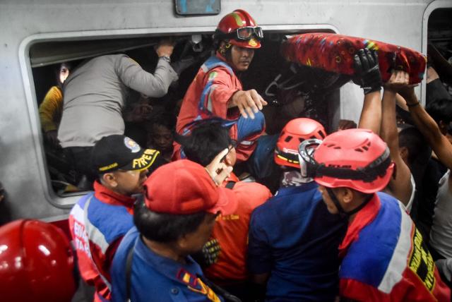 Rescuers work at the site of a train collision after a passenger train locomotive pierced through the rear car of a commuter train at Bekasi Timur station in Bekasi, West Java on April 28, 2026. (Photo by Rezas / AFP)