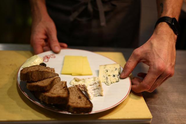 A cook prepares a cheese platter during dinner service at the French restaurant Gigi’s in the Brooklyn borough of New York on April 26, 2026. Hugo Hivernat's restaurant was only open for a few days before he got dragged into New York City's cost of living row over a portion of half chicken priced at $40. For some on social media, the cost highlights how dining has become prohibitively expensive in the most populous US city. But Hivernat insists his business is barely making a profit. (Photo by CHARLY TRIBALLEAU / AFP)